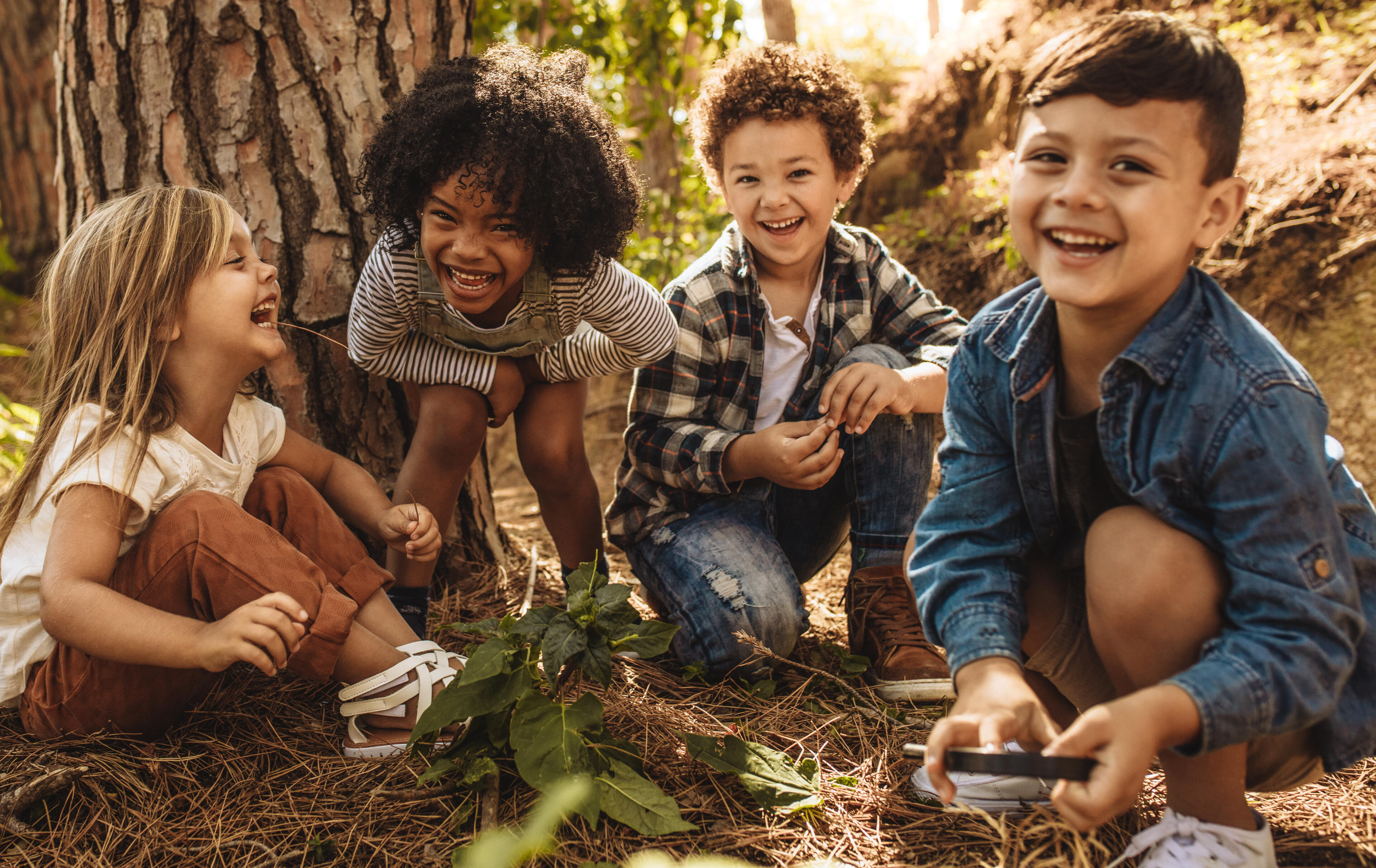 Four elementary school children laughing while out in nature. Four elementary school children having fun by laughing while out in nature.